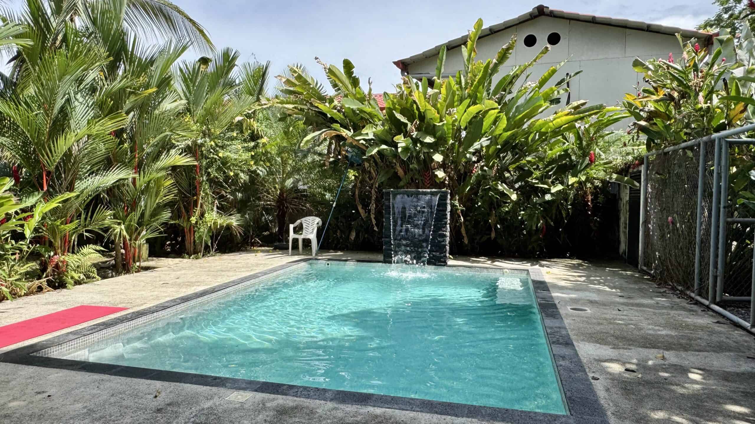 Pool with waterfall feature and tropical garden between the two lots