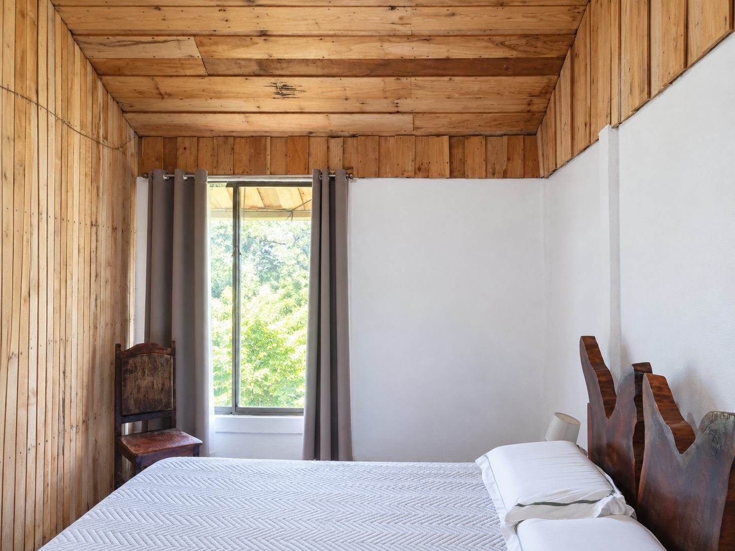 Bright bedroom with a garden window and a live-edge wooden headboard