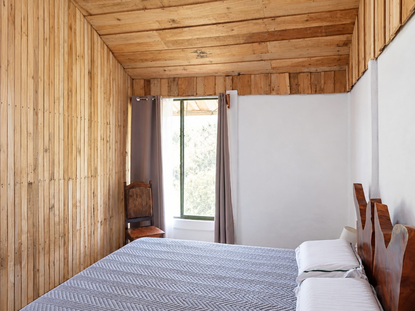 Bedroom with natural wood walls and ceiling and a live-edge wooden headboard