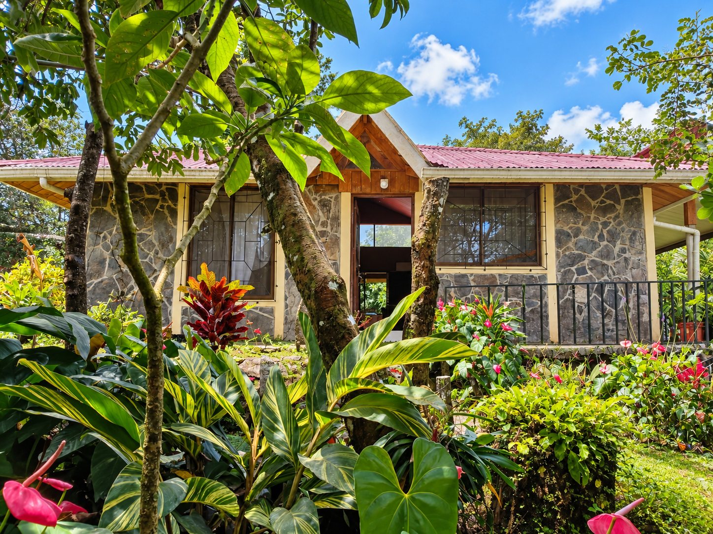 Stone and stucco house behind tropical gardens in Bijagua de Upala