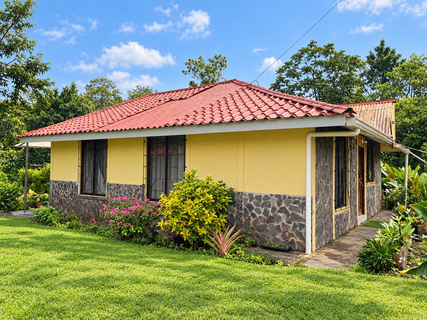 Yellow house with red tile roof and lawn on the Bijagua de Upala property