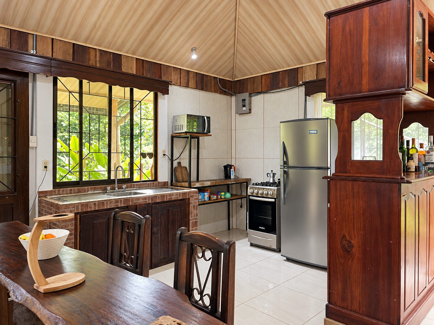 Kitchen with gas range, refrigerator and carved wooden bar cabinet