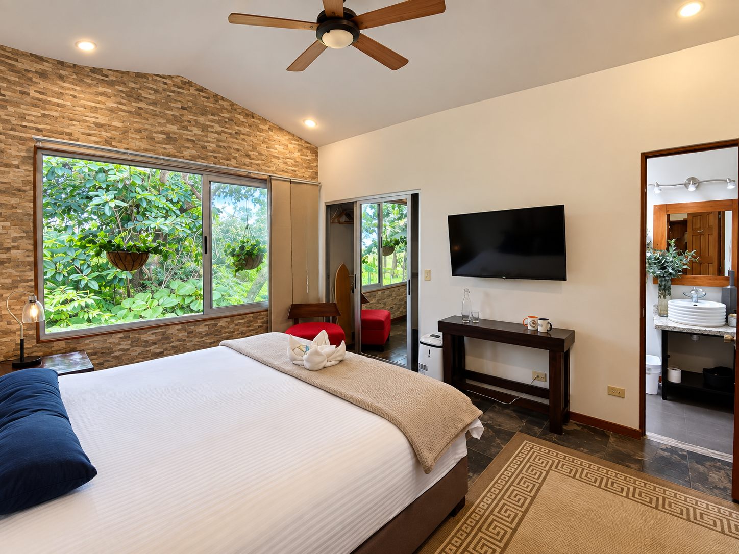Bedroom with a stone feature wall, ceiling fan and big garden window