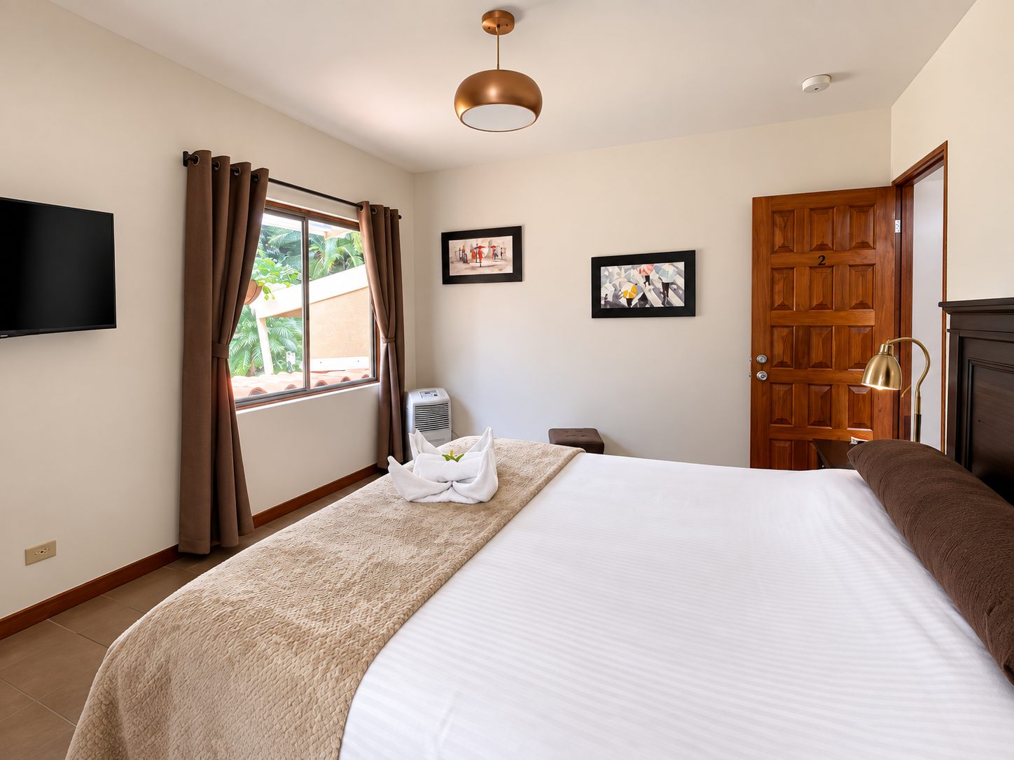 Bedroom with a large bed, wall TV and garden window