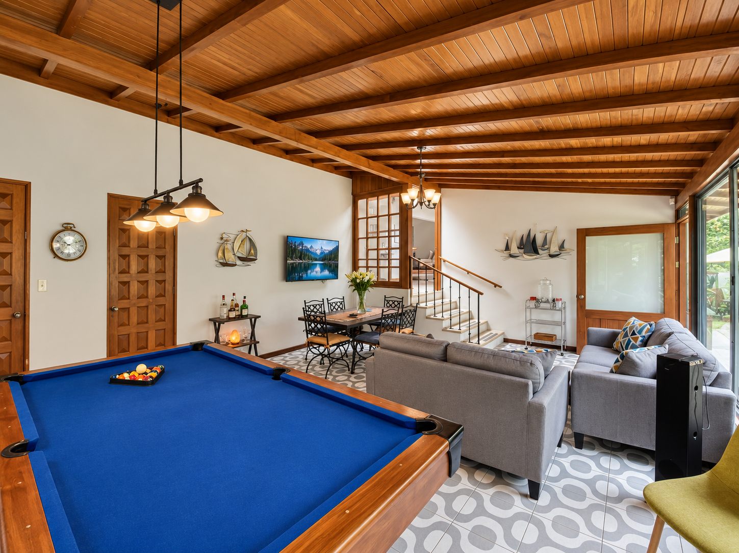 Family room with pool table, sofas and dining area under a wooden ceiling