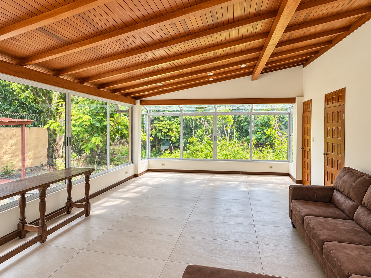 Glass-walled garden room with sofa and wooden ceiling
