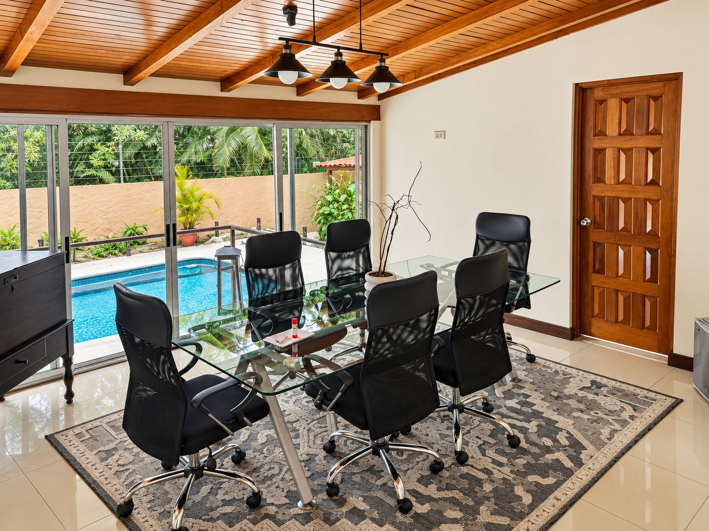 Meeting room with a glass table and office chairs overlooking the pool