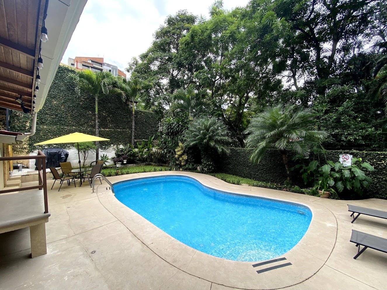 Pool deck with umbrella and loungers in a walled garden