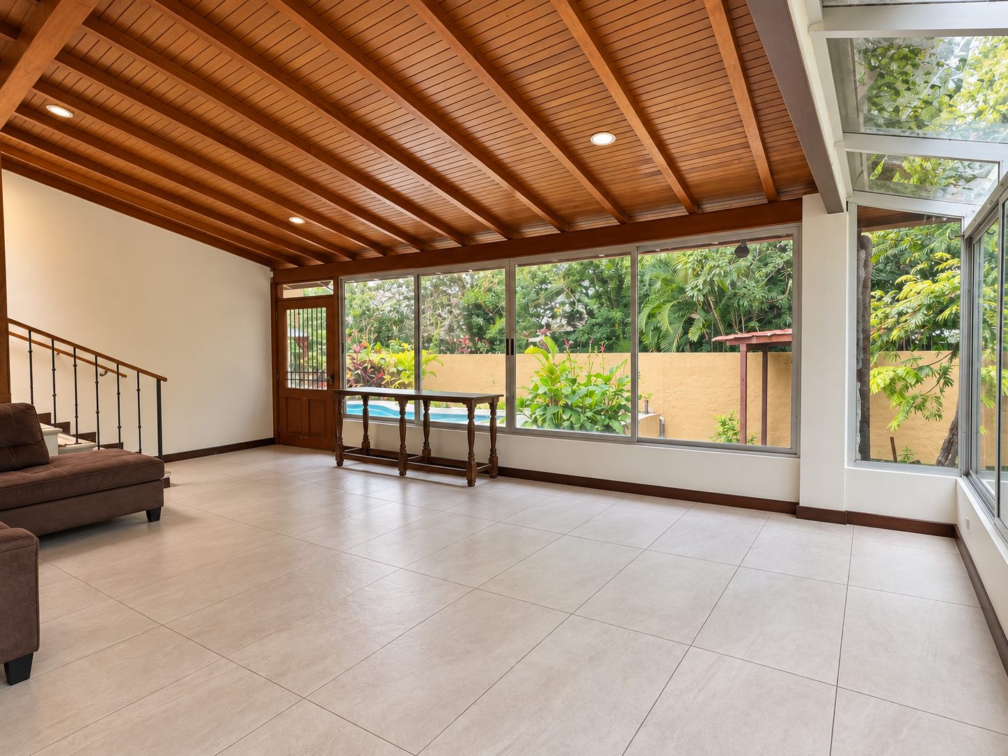 Bright room with a wooden ceiling and a glass wall looking out to the pool